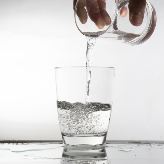 Remplissez l&#39;eau dans le verre sur un fond blanc