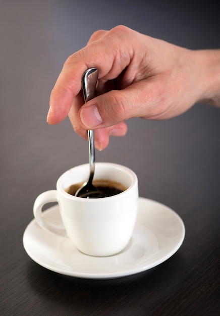 Remuant à la main tasse de café expresso avec cuillère