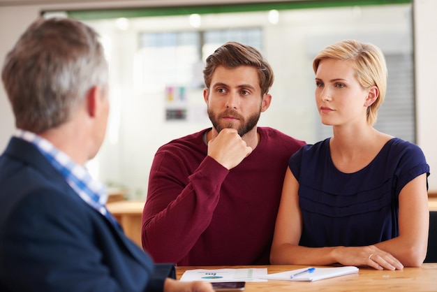 Rencontre avec leur conseiller financier Jeune couple discutant de plans d'investissement avec un conseiller financier