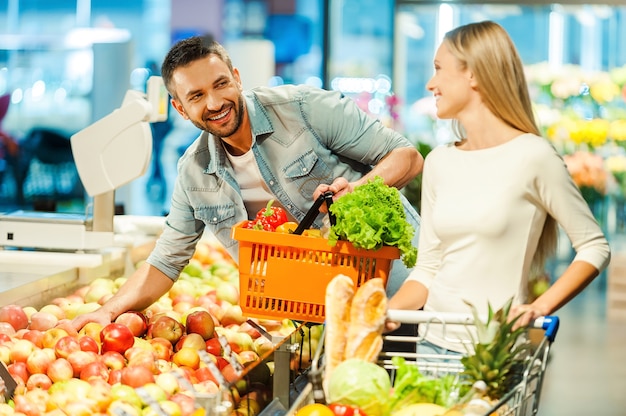 Rencontre en supermarché. Beau jeune couple choisissant des produits dans un supermarché et se regardant avec le sourire