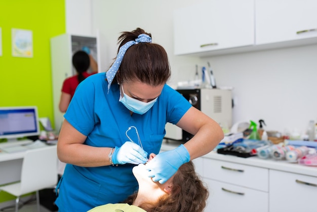 Photo rendez-vous chez le dentiste dans une clinique dentaire en plaçant des verrous d'accolades sur les dents et en tirant l'arc pour