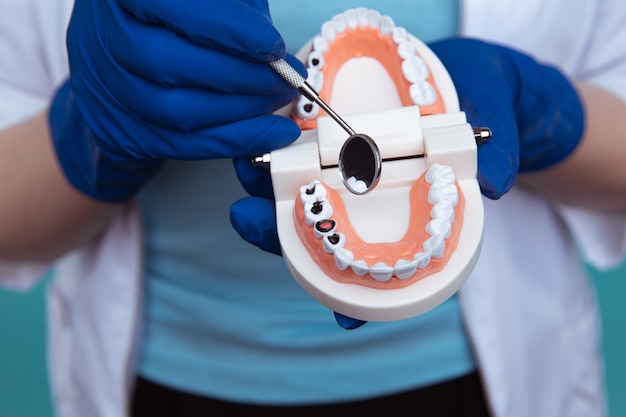 Rendez-vous chez le dentiste, instruments de dentisterie et concept de contrôle d'hygiéniste dentaire avec prothèses dentaires et instruments de stomatologie sur gris foncé. Des examens réguliers sont essentiels à la santé bucco-dentaire