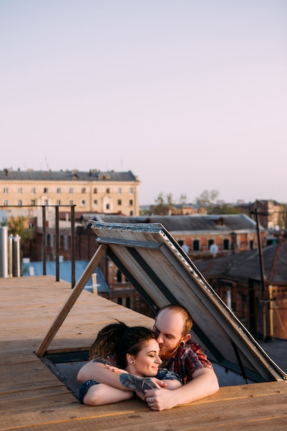 Rendez-vous romantique sur le toit. Relations d'appel d'offres. Heureux jeune couple câlins, se concentrer sur le premier plan avec un espace libre. Agréable moment ensemble au sommet du monde, fond urbain