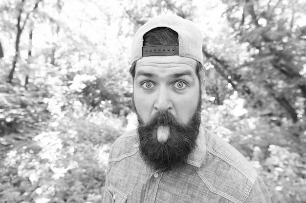 Rendre la vie digne d'être vécue jour d'été amusant homme barbu à la recherche d'un drôle d'homme barbu brune porter une casquette dans la forêt sur fond d'arbres homme brune brutale faisant selfie mec mature avec barbe en bois