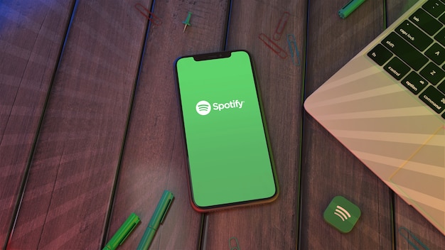 Rendu 3D d'un smartphone affichant le logo de l'application Spotify sur un bureau en bois