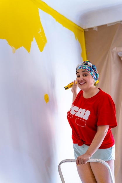 Rénovation d'un mur jaune Une femme d'âge moyen apporte de la couleur à sa maison