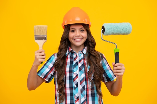 Rénovation pour chambre d'enfant Petite fille en casque de protection et pinceau pour peindre les murs