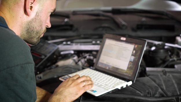 Un réparateur automobile diagnostique une voiture à l'aide d'un atelier informatique