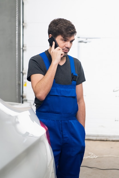 Un réparateur barbu en uniforme parle sur un téléphone portable