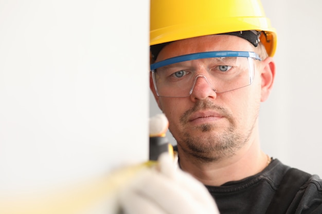 Réparateur en casque et masque, mesure le ruban à mesurer