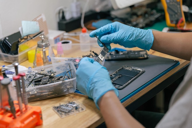 réparateur choisissant la pièce électronique à assembler avec le téléphone portable avec les outils sur le bureau