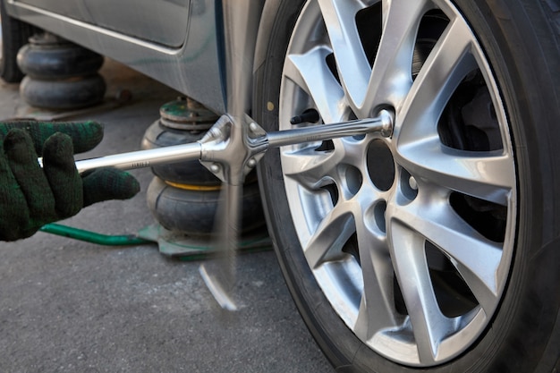 Le réparateur dévisse la roue pour la remplacer avec une clé à molette. Changement saisonnier des pneus de voiture.