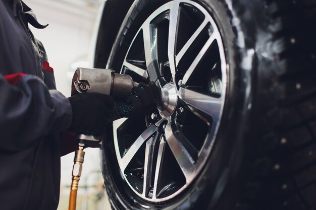 Photo le réparateur équilibre la roue et installe le pneu sans chambre de la voiture sur l'équilibreuse dans l'atelier.