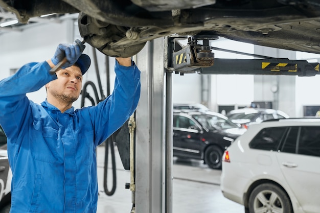 Réparateur essayant de supprimer les détails obsolètes du châssis de la voiture