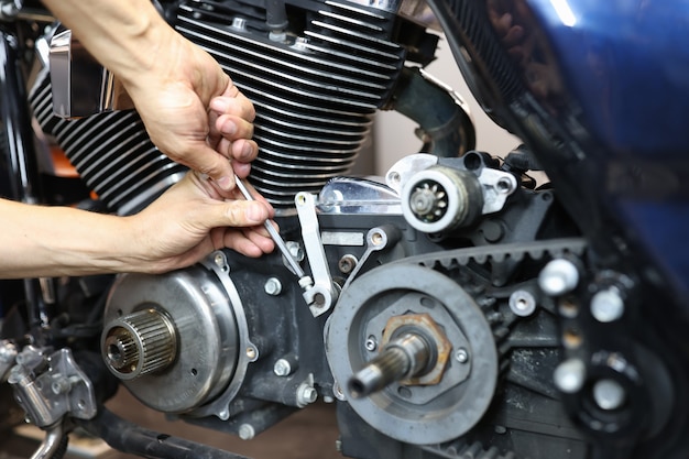 Réparateur principal réparant la moto dans la réparation et l'entretien de plan rapproché d'atelier des motos