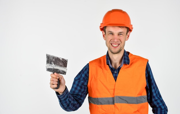 Réparateur professionnel dans la construction et la construction de casques architecte qualifié répare et répare les outils de carrière d'ouvrier ingénieur pour la réparation jeune homme dans un casque dur constructeur d'hommes utilise une spatule