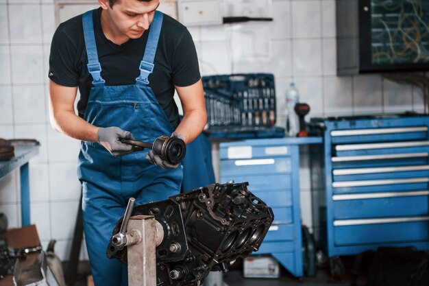 Réparateur professionnel dans un garage fonctionne avec un moteur automobile cassé