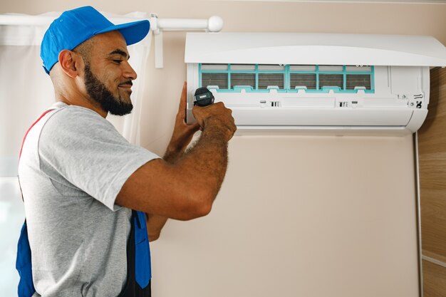 Photo réparateur professionnel installant un climatiseur dans une pièce