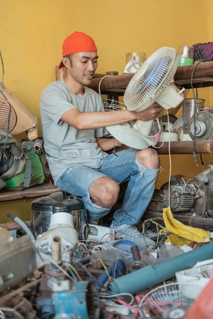 Réparateur tenir les ventilateurs assis autour de pièces électroniques dans un atelier de service