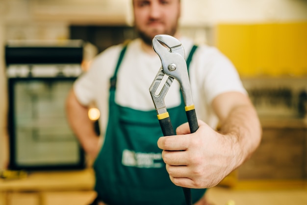 Réparateur en uniforme détient une clé, bricoleur