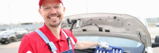 Un réparateur en uniforme rouge a ouvert la voiture à capot dans la rue