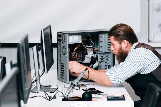 Réparation de composants de réparation dans l'unité informatique. Ingénieur barbu assemblant CPU dans un atelier de réparation. Rénovation électronique, réparation, concept de développement