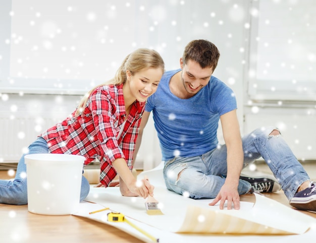réparation, construction, travail d'équipe et concept de maison - couple souriant enduisant de papier peint avec de la colle
