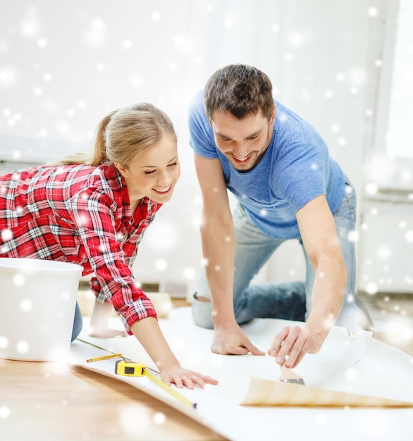 réparation, construction, travail d'équipe et concept de maison - couple souriant enduisant de papier peint avec de la colle