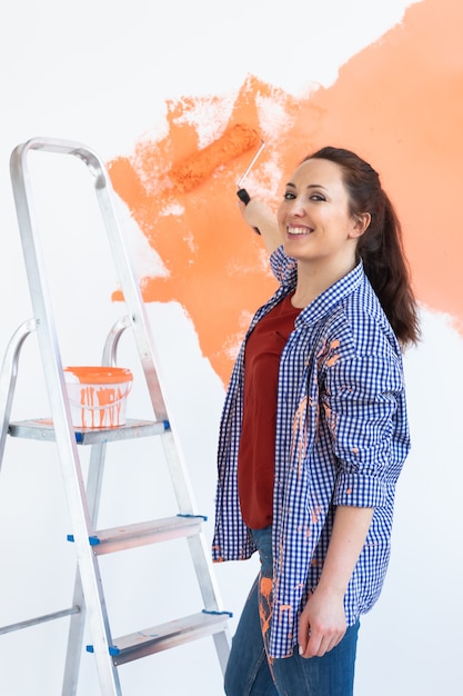 Photo réparation dans l'appartement. heureuse femme peint le mur avec de la peinture.