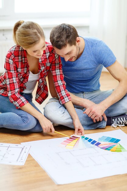 réparation, design d'intérieur, construction, rénovation et concept de maison - couple souriant regardant des échantillons de couleur à la maison