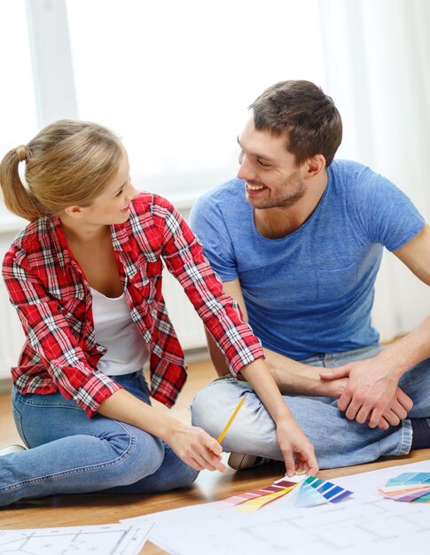 réparation, design d'intérieur, construction, rénovation et concept de maison - couple souriant regardant des échantillons de couleur à la maison