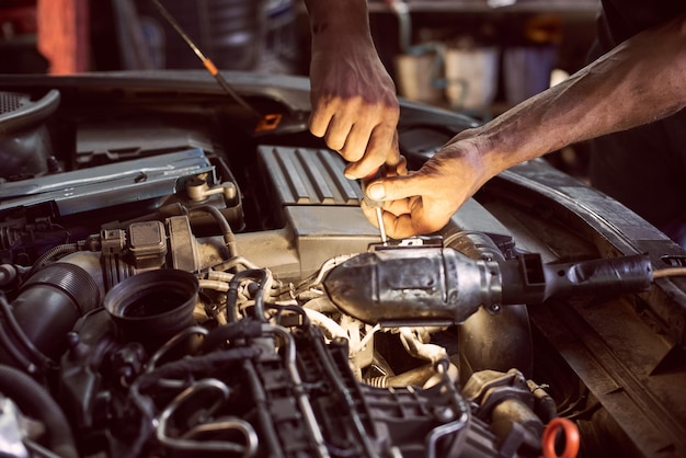 Réparation du moteur diesel avec un tournevis et une lampe de poche aidant Vue rapprochée du moteur automatique sale et des mains coupées