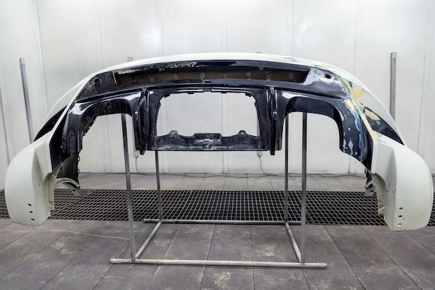 Réparation du pare-chocs arrière d'une voiture blanche après un accident à l'aide de mastic multicolore dans un atelier de peinture de véhicules dans une chambre spéciale