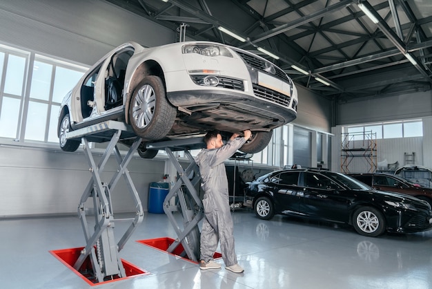 Réparation De Mécanicien Voiture Sur Ascenseur Dans L'atelier De Mécanique Ou Garage, Intérieur De L'atelier De Réparation Automobile