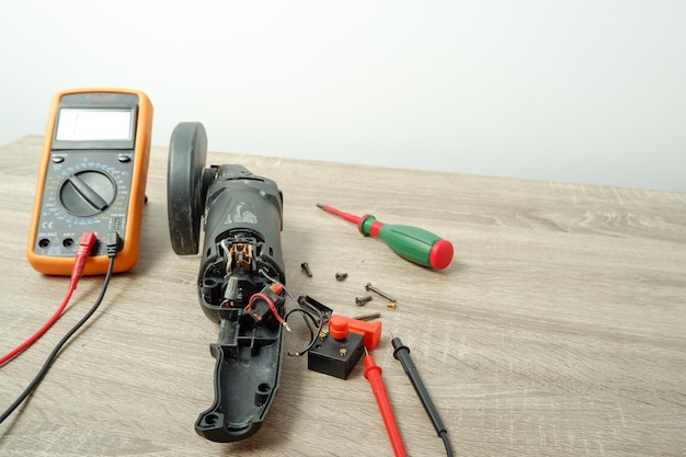 Réparation d'outils électriques Meuleur d'angle démonté pour réparation sur la table Multimètre de tournevis