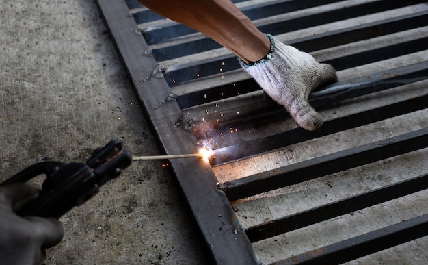 Réparation de porte de fer, acier de soudure de main de travailleur