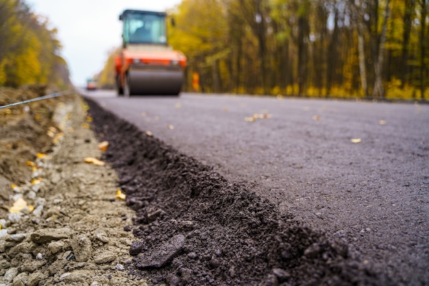 Réparation de routes, compacteur pose l'asphalte. Machines spéciales lourdes. Finisseur d'asphalte en opération. Vue de côté. Fermer.