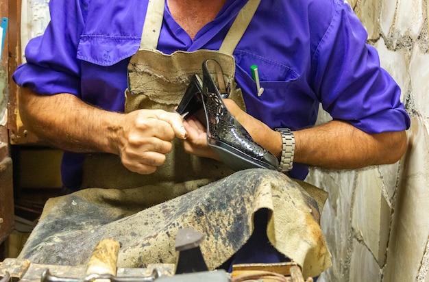 Réparation traditionnelle de chaussures pour femmes en coupant l'excédent de la tige avec une lame de coupe abaissant