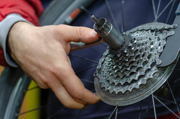 Réparation de vélo de montagne Le maître tient dans sa main un outil pour retirer le fouet de chaîne de l'extracteur de pignon de cassette