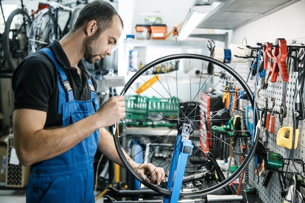 Réparation de vélos en atelier, l'homme travaille avec roue