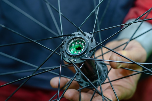 Réparation de vélos Changement de la lubrification et nettoyage des roulements des moyeux de vélo Nouveaux roulements brillants installés dans le moyeu Texture de la peau en gros plan Mains travailleuses