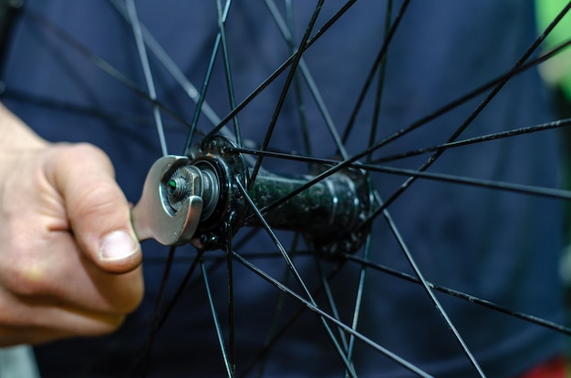 Réparation de vélos Remplacement de la lubrification et du nettoyage des roulements de moyeu de vélo Entre les mains des clés professionnelles maîtresses Gros plan sur les mains assidues