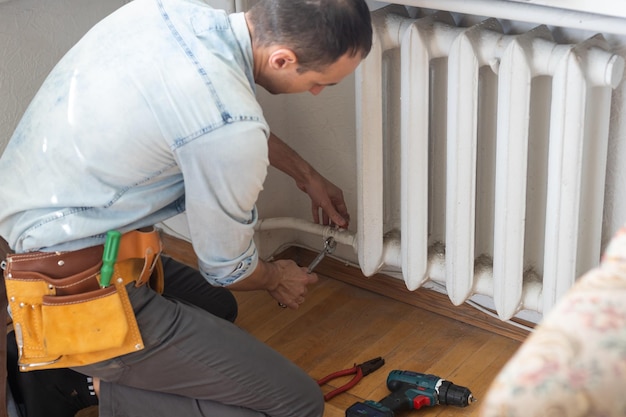 Photo réparer le gros plan du radiateur de chauffage. homme réparant le radiateur avec une clé. enlever l'air du radiateur.