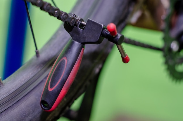 Réparer un vélo de montagne dans l'atelier Remplacement d'une vieille chaîne rouillée par une nouvelle Outil pour faire le retrait et l'installation de la chaîne en gros plan Fond vert