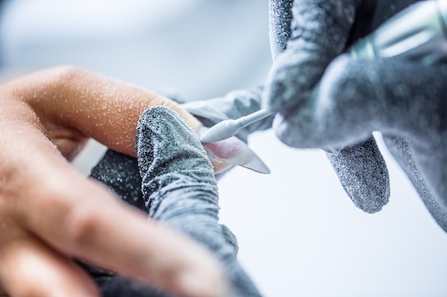Réparer de vieux ongles en gel avec un broyeur d'ongles dans un salon de manucure