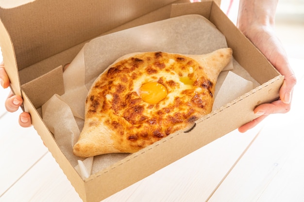 Repas de cuisine géorgienne traditionnelle Khachapuri adjara. Pain cuit au four avec fromage et garniture aux œufs. Collation pâtissière nationale.