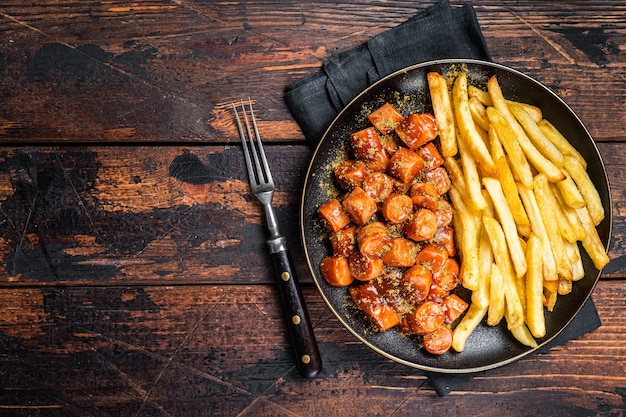 Repas de currywurst allemand curry wurst avec frites servi dans une assiette Fond en bois Vue de dessus Espace de copie