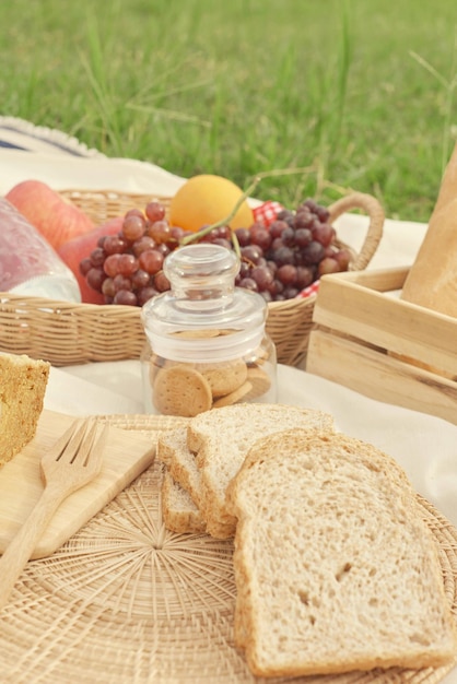 Repas de pique-nique de concept de pique-nique sur le tissu blanc se composant d'un panier d'une bouteille d'eau