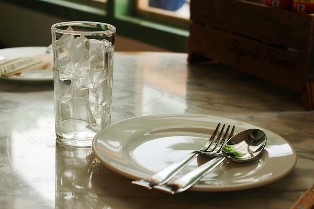 le repas a la plaque blanche, le verre de glace, la fourchette et la cuillère sur la table de marbre