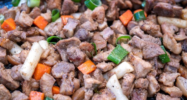 Photo un repas de porc noir frit en corée marché traditionnel délicieuse cuisine coréenne avec carotte et échalotte oignon vert copier l'espace de près